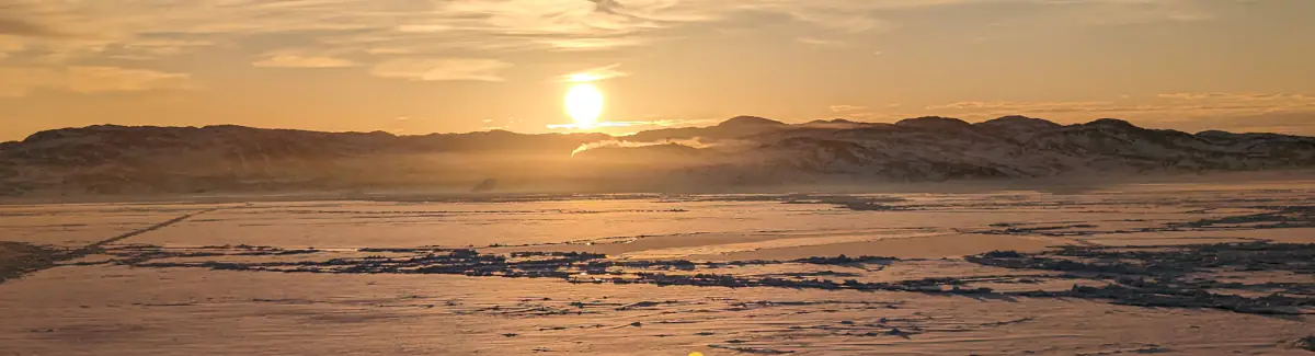 Blick auf die eisbedeckte Diskobucht bei Sonnenaufgang.