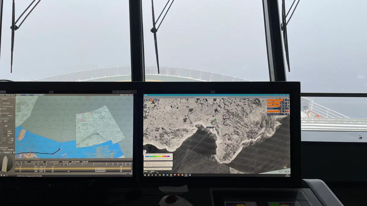 View from a ship’s bridge sailing through icy waters under foggy conditions.