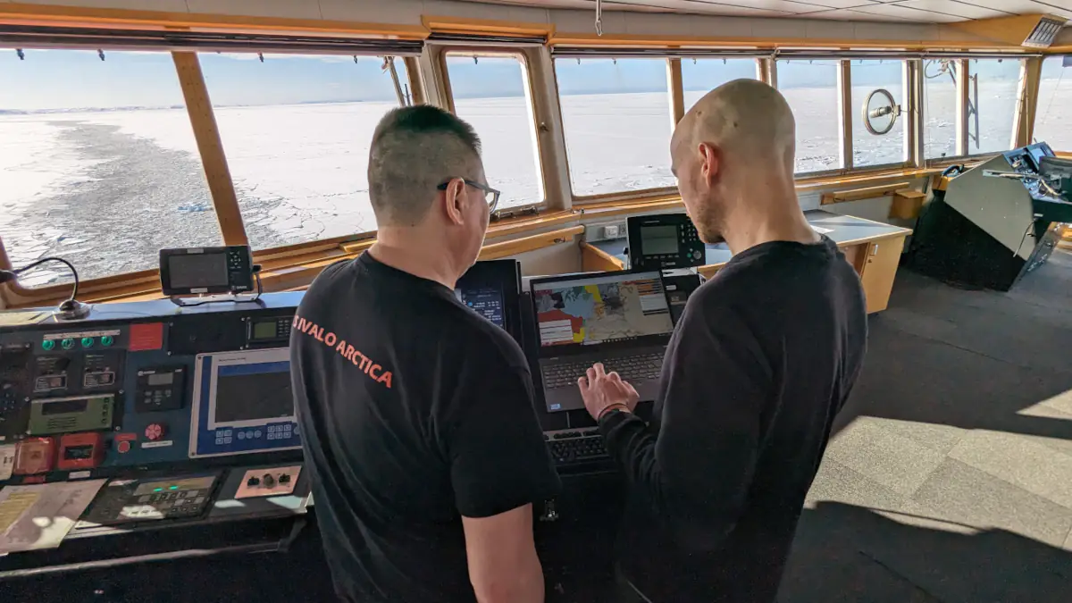 Two people working with IcySea on a vessel's bridge.