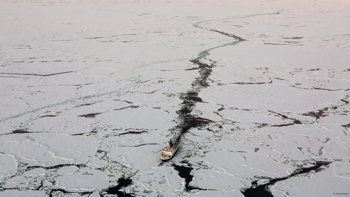 Aerial view of the icebreaking vessel Polarstern sailing through sea ice.